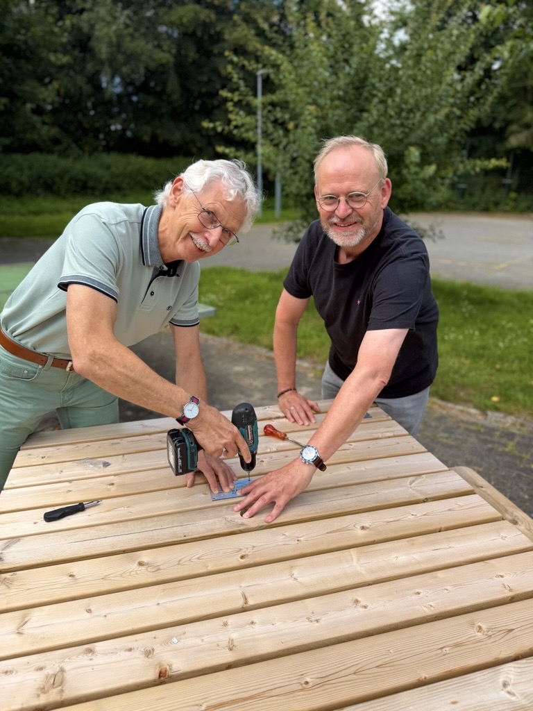 Dr. Itzek-Westhus und Bernhard Hövelmann bringen das neue Spendenschild an der Sitzbank an